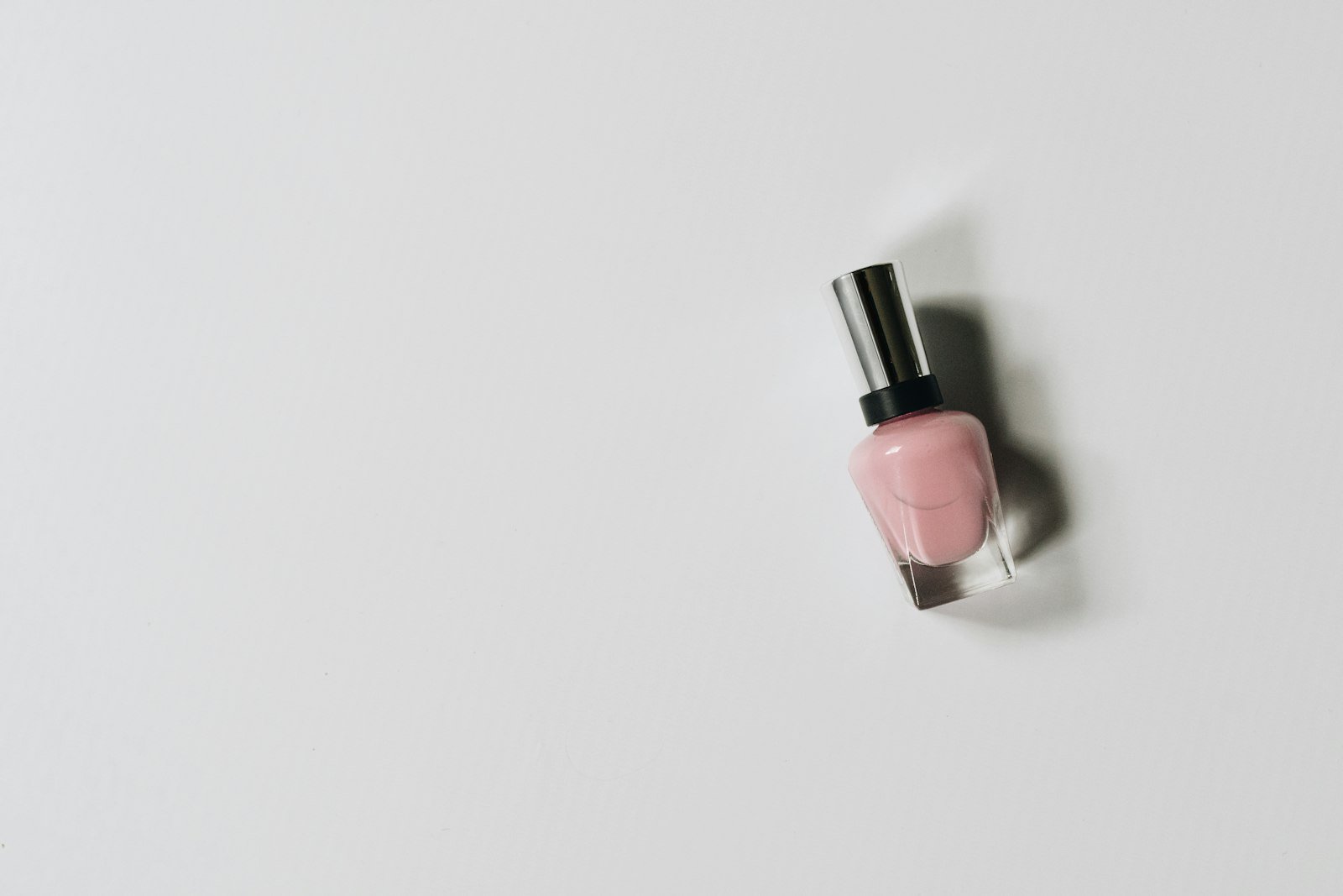 A single bottle of pink nail polish on a white surface