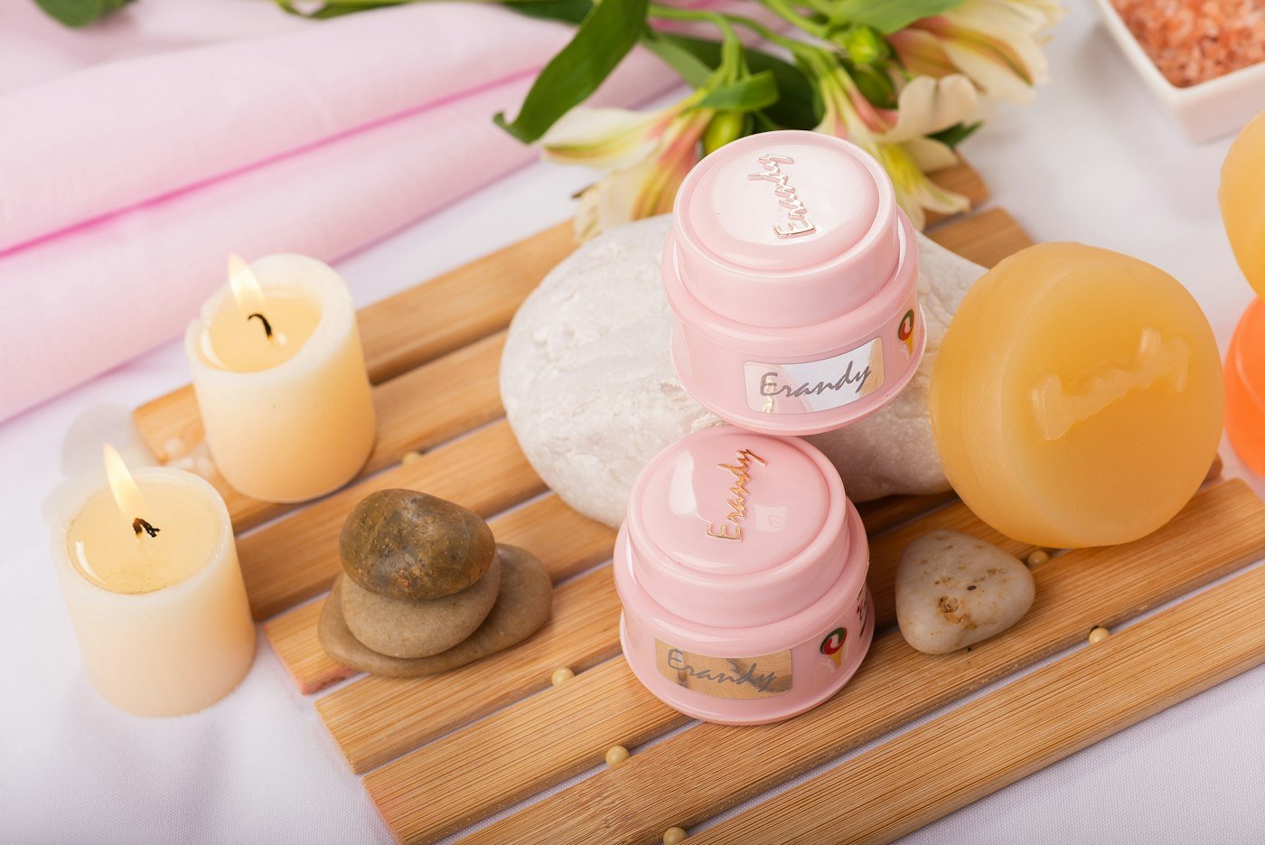 Candles, soaps and pink skincare on a wooden spa tray