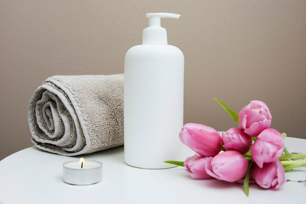 Pink tulips beside a rolled towel and lotion bottle