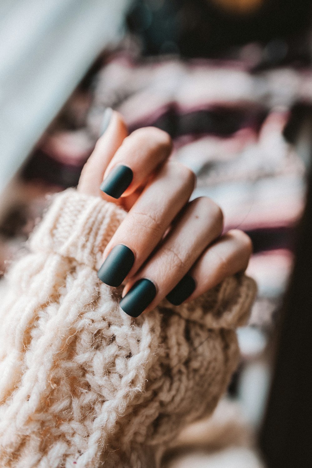 Dark glossy manicure against a cream knit