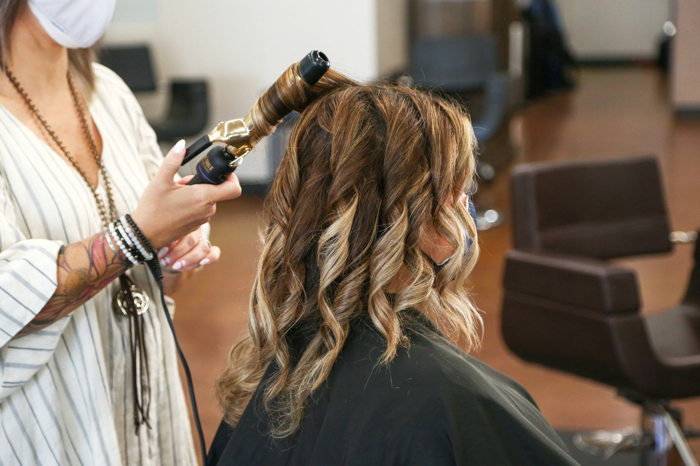 Stylist curling a client's hair with an iron