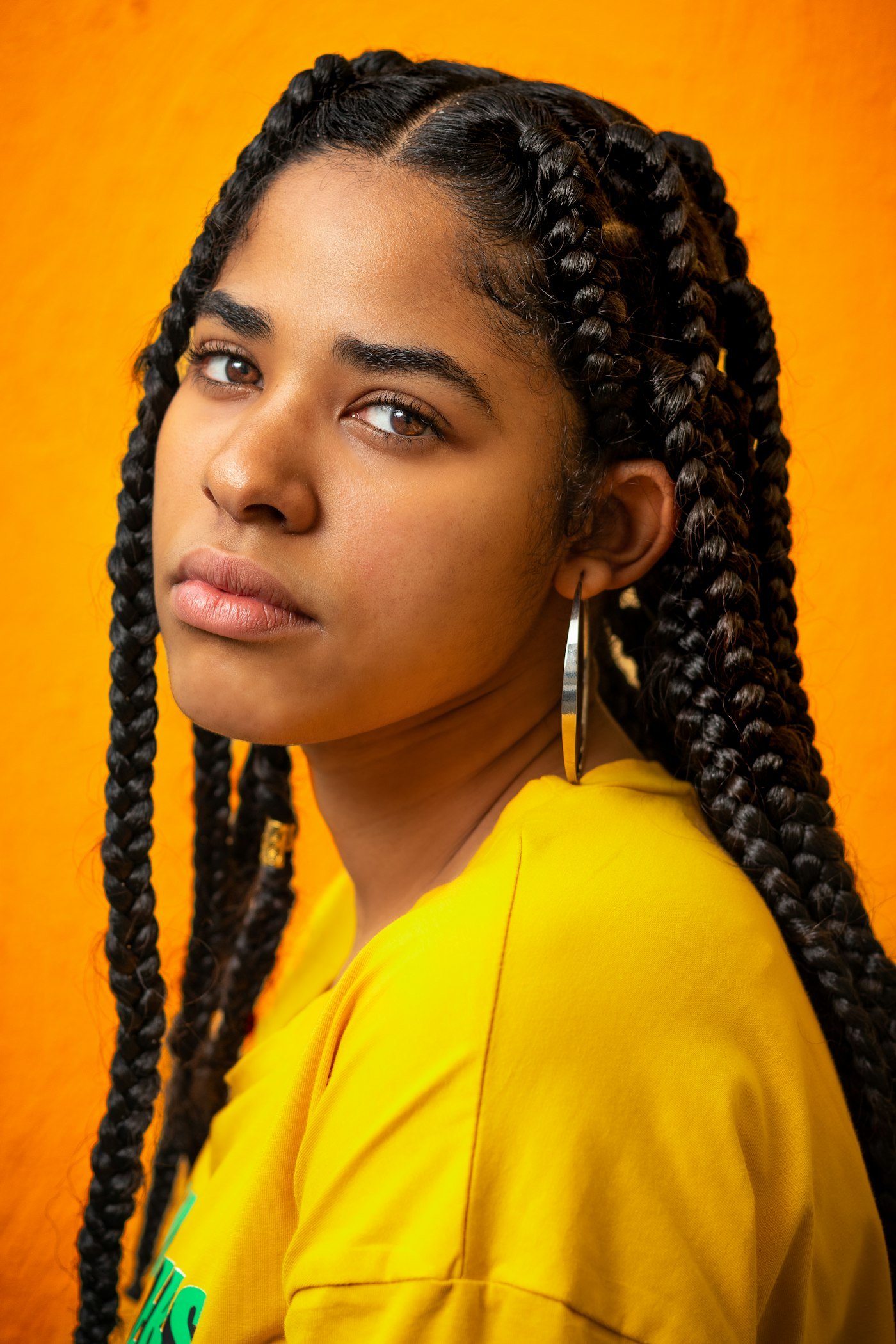 Woman with long black braids against a bright yellow background