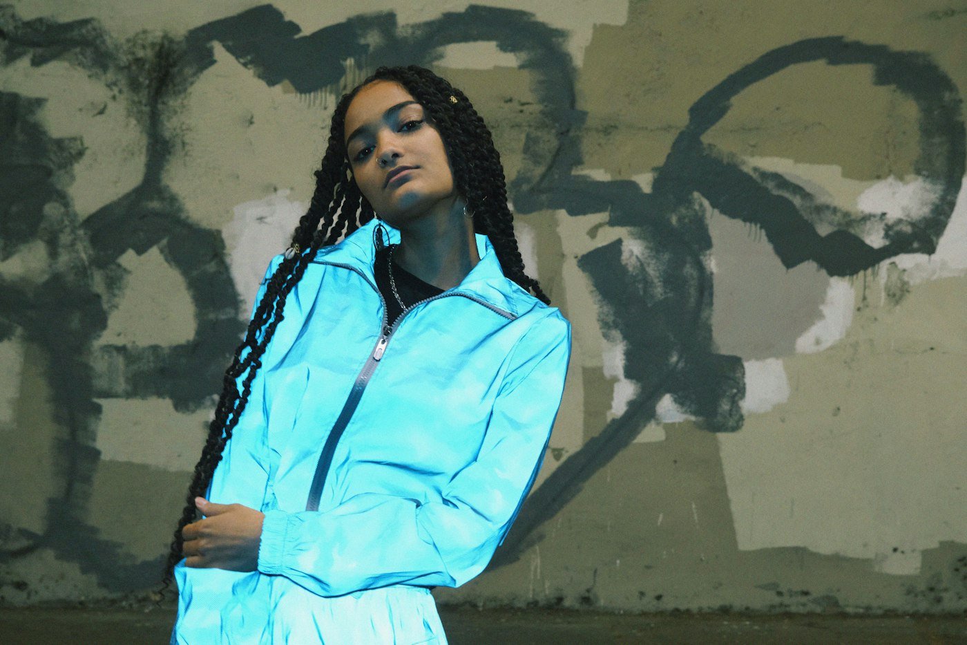 Woman with long locs in front of graffiti