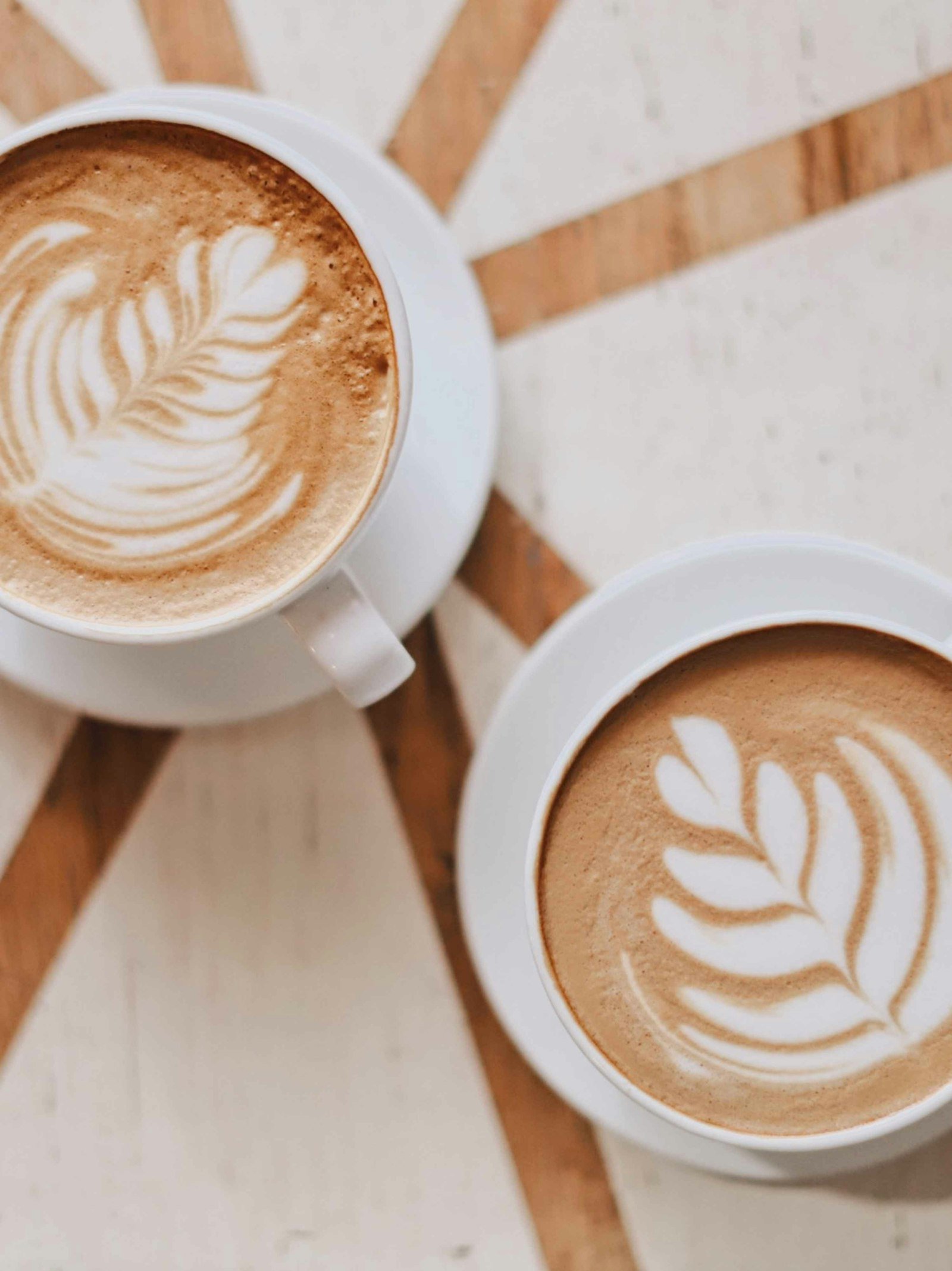 Two lattes with leaf art on a table