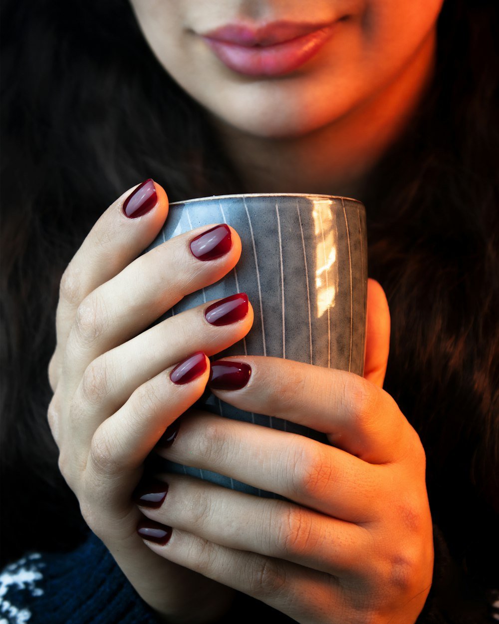 Dark manicure around a mug