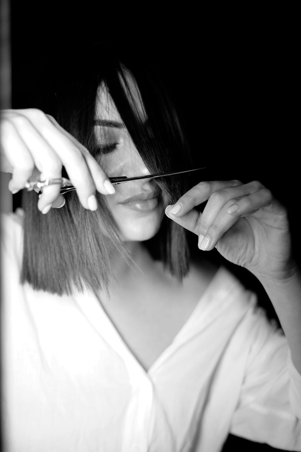 Stylist trimming hair with scissors in black and white