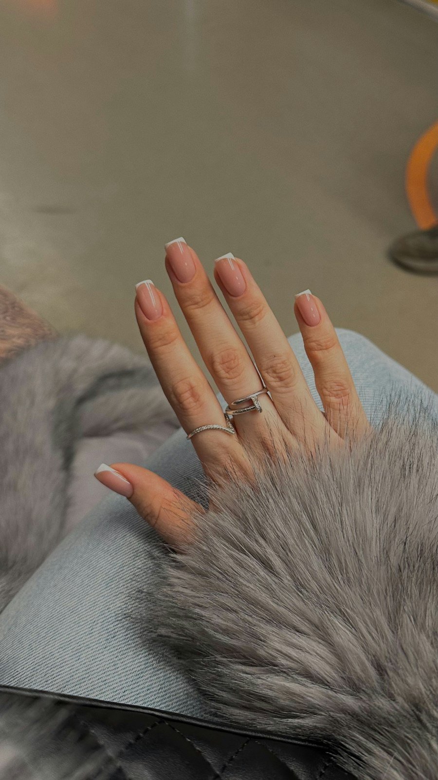 Nude manicure with a ring resting on grey fur