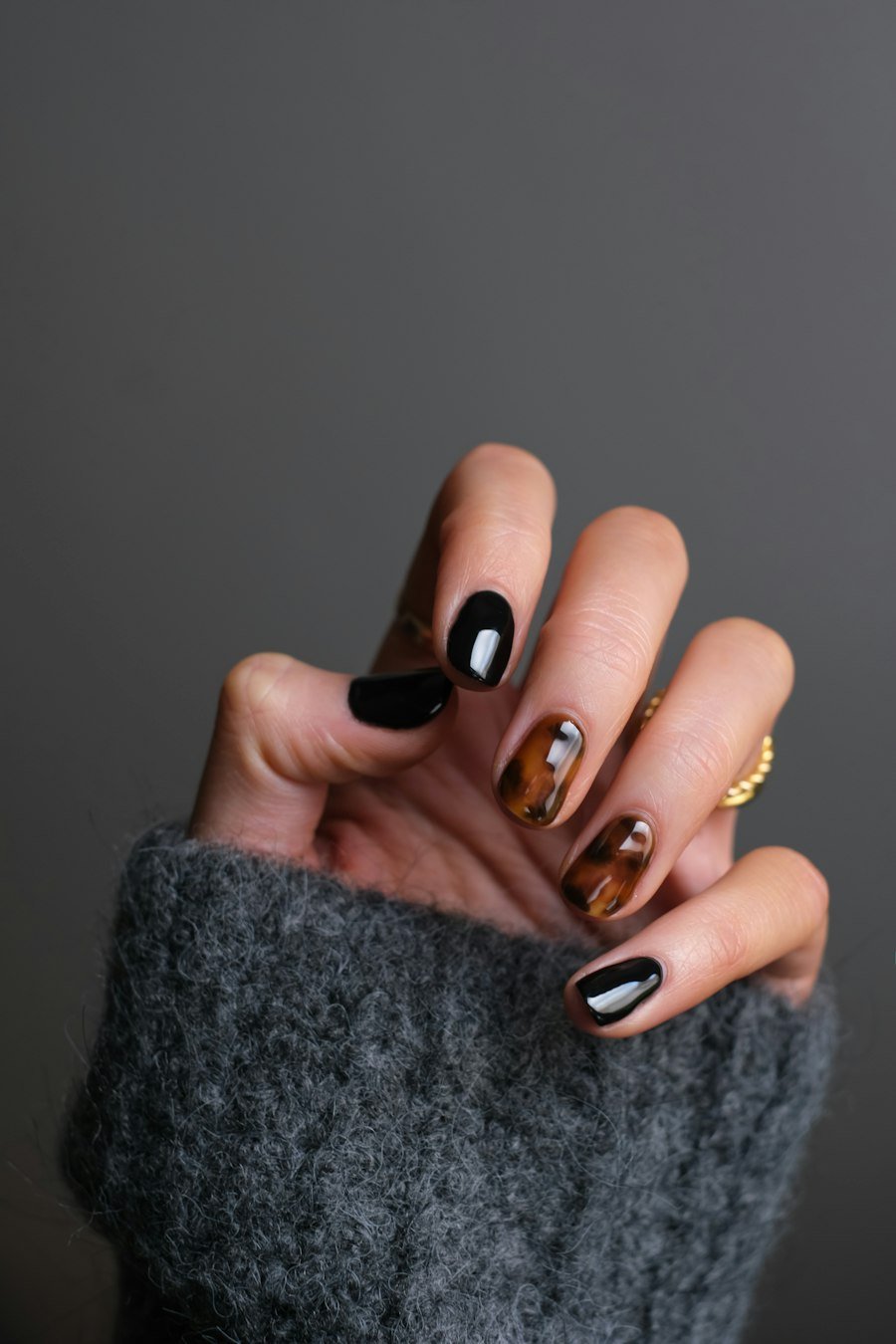 Black and tortoiseshell nail art with a gold ring