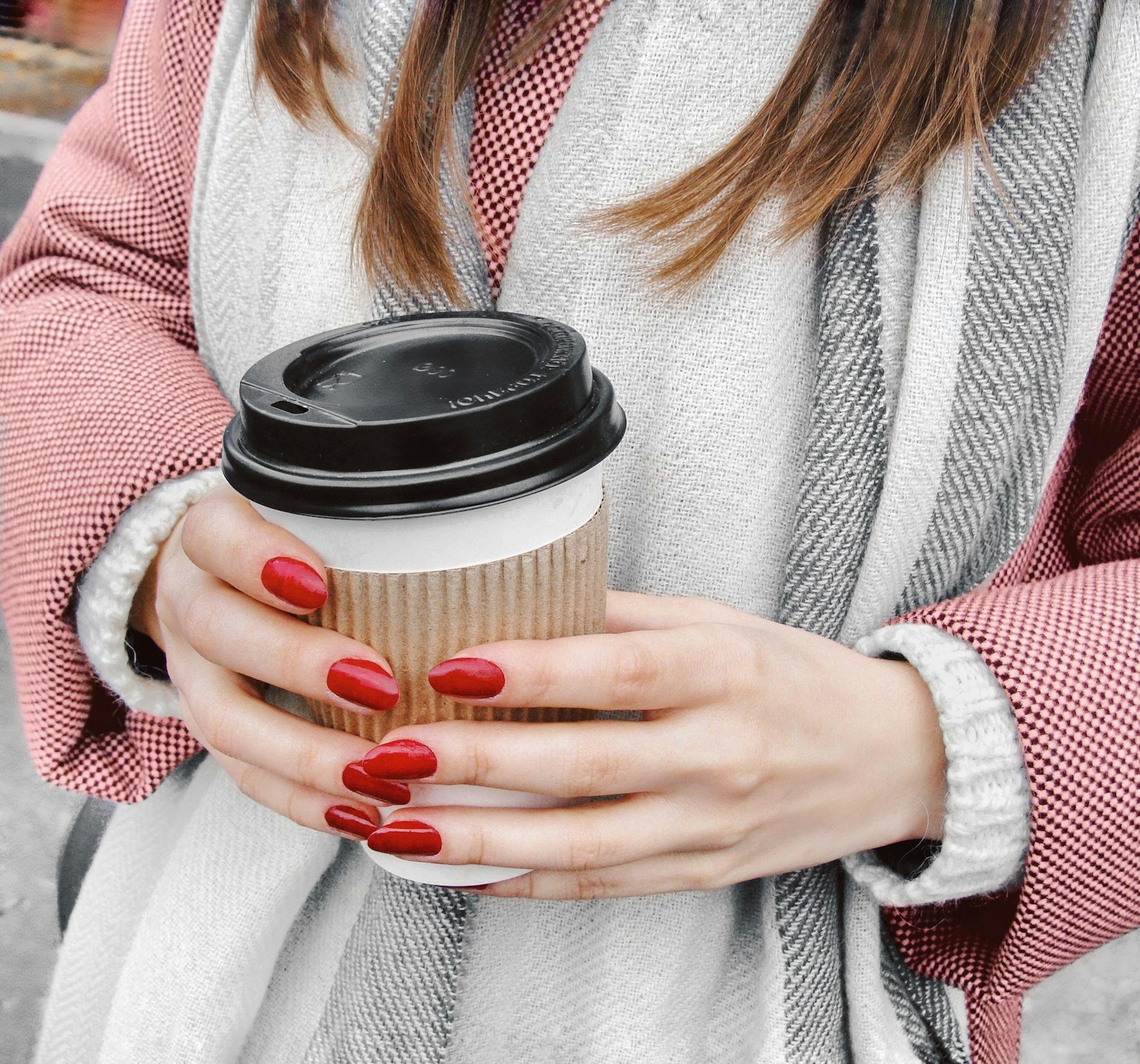 Glossy red manicure holding a coffee cup