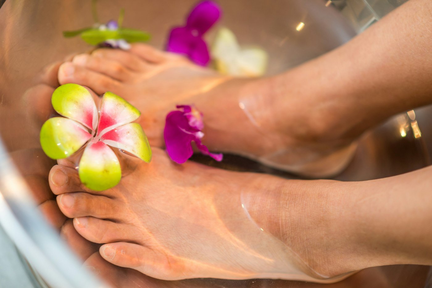 Feet in a pedicure bowl decorated with fresh flowers